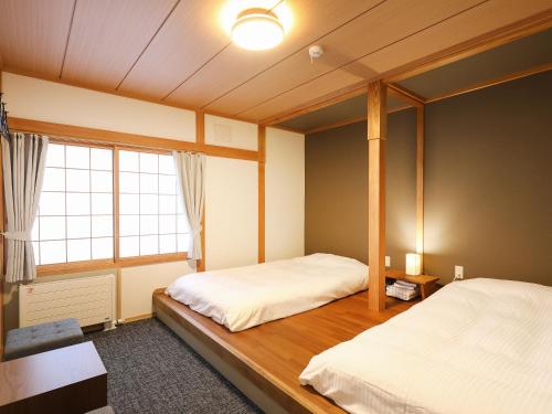 a bedroom with two beds and a window at RONENAI BASE in Biei