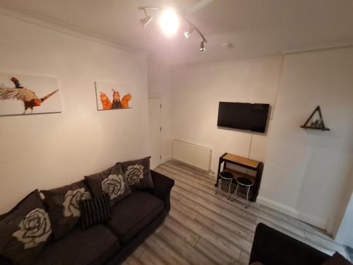 a living room with a couch and a flat screen tv at City Centre Apartment in Aberdeen