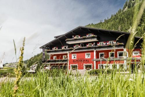 a large red building in front of a mountain at Hotel Alpenroyal - The Leading Hotels of the World in Selva di Val Gardena