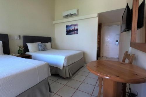 a hotel room with two beds and a table at La Concha Beach Hotel & Club in La Paz
