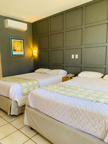 a hotel room with three beds in a room at La Concha Beach Hotel & Club in La Paz