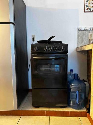 a black stove in a kitchen next to a refrigerator at Conexión Perfecta Entre Playa y Aviones in Tampico