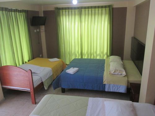 two beds in a room with green curtains at Hotel Villa Santa Ana in Quillabamba