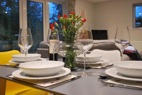 a table with plates and glasses and a vase of flowers at Stylish-Stays Covert Cottage, Fleet Stylish Cottage, Parking, Patio, Dog Friendly, EV in Fleet