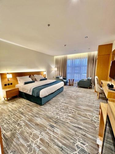 una grande camera d'albergo con un letto e una grande finestra di فندق كوخ الضباب النماص a Al Namas
