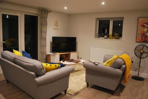 a living room with two chairs and a television at Stylish-Stays Covert Cottage, Fleet Stylish Cottage, Parking, Patio, Dog Friendly, EV in Fleet