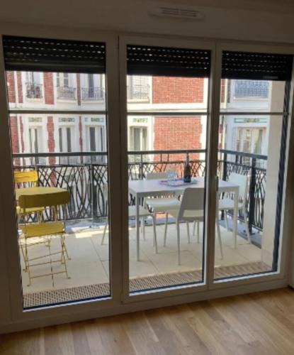 een kamer met glazen schuifdeuren, een tafel en een balkon bij Very nice 40 m quiet in Suresnes with parking in Suresnes