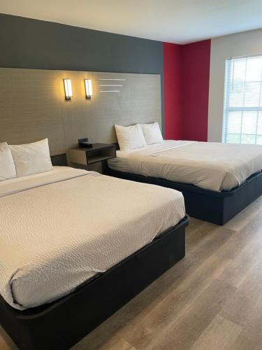 a hotel room with two beds and a red wall at Ramada by Wyndham Studio Suites Dothan in Dothan