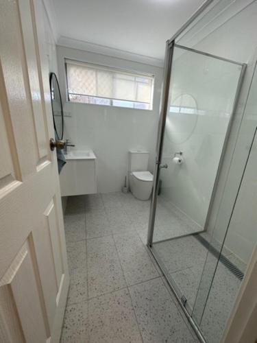 a bathroom with a glass shower and a toilet at Harbour View 49 Urch Street Unit 8 in Geraldton