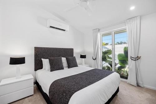 Un dormitorio blanco con una cama y una ventana. en Family & Pet-Friendly Luxury Near Hastings St, en Noosa Heads