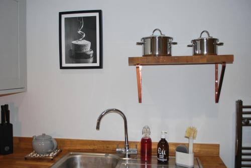 a kitchen sink with two pots on a shelf at Stylish Hampshire Cottage, Parking, Patio, Dog Friendly, Local Restaurants in Fleet