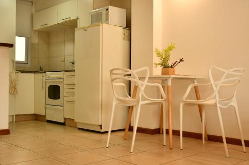 Una cocina con sillas blancas, una mesa y un refrigerador. en tu dpto en ROSARIO, en Rosario