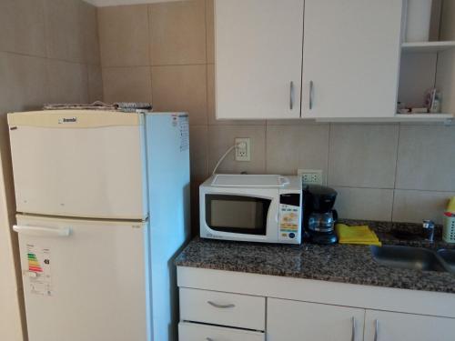 a kitchen with a white refrigerator and a microwave at MRU Colón aparts in Colón