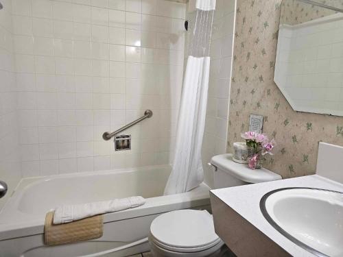 a bathroom with a toilet and a tub and a sink at Ocean Marina Hotel in Port Alberni
