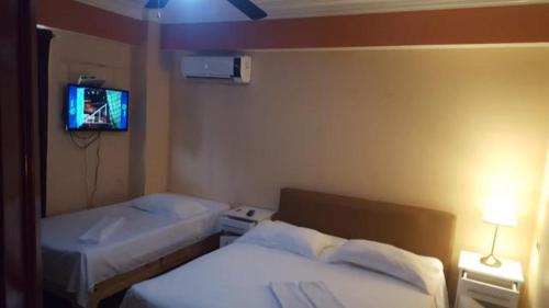 a hotel room with two beds and a tv at Residencial Las Palmeras de Willy Boca Chica in Boca Chica