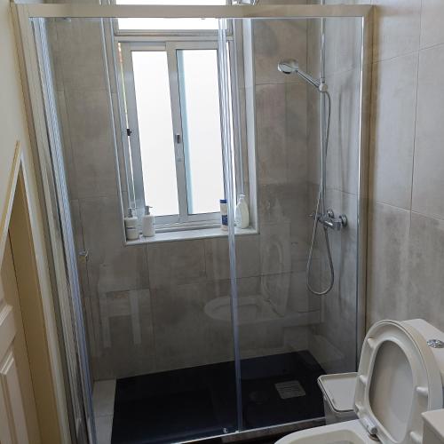 a bathroom with a shower and a toilet and a window at Guesthouse Monsanto in Porto