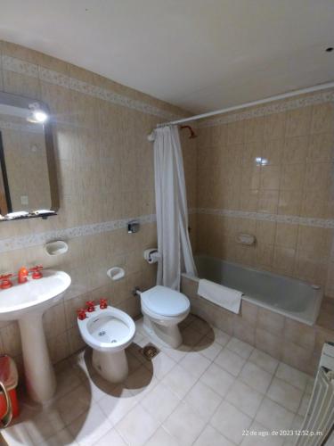 uma casa de banho com um WC, uma banheira e um lavatório. em Hotel Victoria em Comodoro Rivadavia