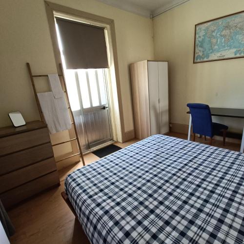 a bedroom with a bed and a blue chair and a door at Guesthouse Monsanto in Porto