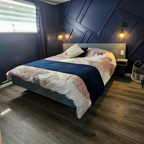 a bedroom with a bed with a blue wall at Le Calvados in Quebec City