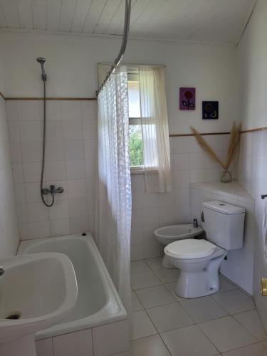 a bathroom with a tub and a toilet and a sink at Casa en barrio de Chacras Las Perdices in Carmelo