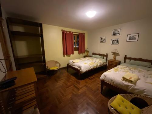 a bedroom with two beds and a table and a desk at La Casa de Zarela in Huaraz