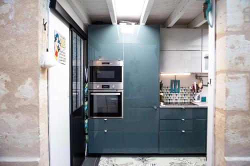 a kitchen with blue cabinets and a stove at Pretty house - near botanical garden in Bordeaux