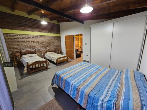 a bedroom with two beds and a brick wall at Alojamiento Zapala - Sakin in Zapala
