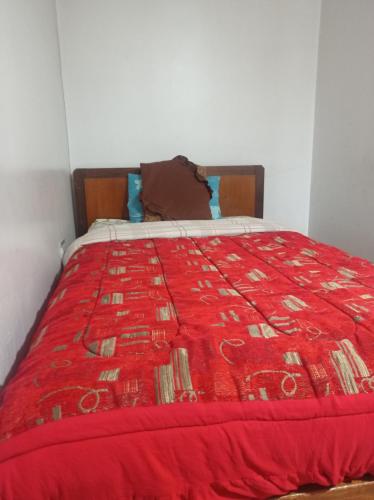 Una cama con un edredón rojo encima. en ESCOCIE-PLAZA G, en Quito