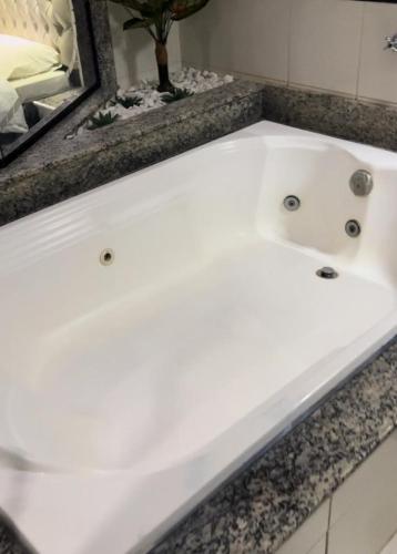 a white bath tub in a bathroom with a mirror at Hotel Tennessee in Bragança Paulista