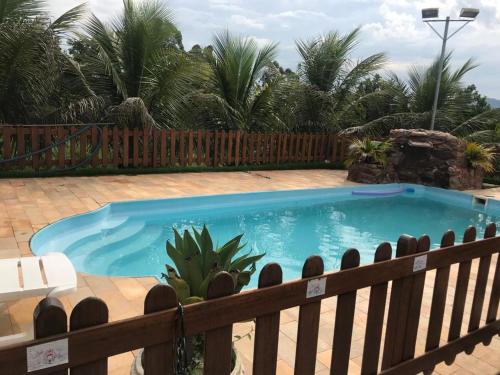 a swimming pool in a yard with a wooden fence at Sítio Santa Terezinha in Divinópolis