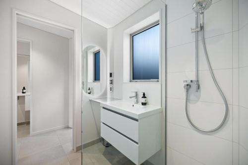 a white bathroom with a shower and a sink at Queenstown Hot Tub Apartment in Frankton Wharf