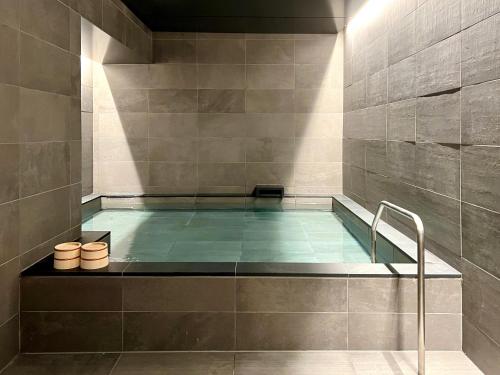 einen Pool im Bad mit einer Fliesenwand in der Unterkunft ABiz hotel in Kyoto