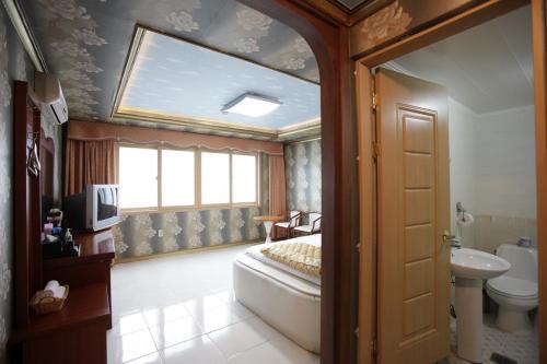 um quarto com uma cama, um lavatório e uma janela em Pataya Motel em Geoje