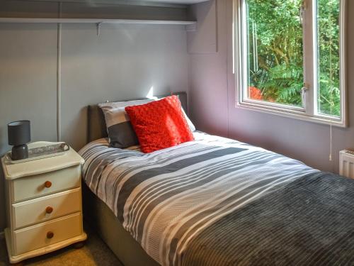 Schlafzimmer mit einem Bett mit einem roten Kissen und einem Fenster in der Unterkunft Meadow View Van - Uk44667 in Neatishead