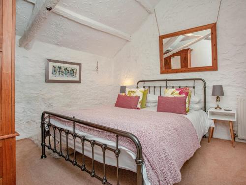 a bedroom with a bed and a mirror on the wall at Mayrose Cottage in Lanteglos