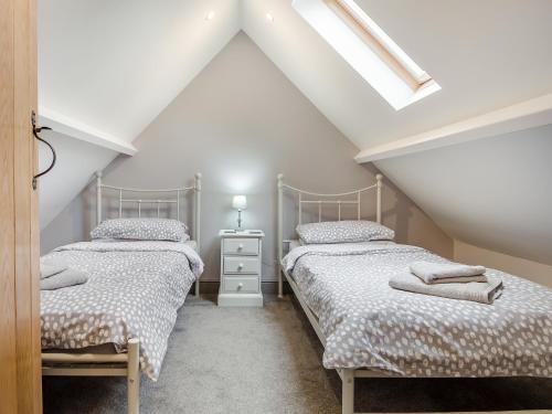 two beds in a attic bedroom with a skylight at The Granary in Great Fransham