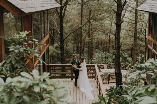 a bride and groom standing on a bridge at Amaya Retreat in Sóc Sơn