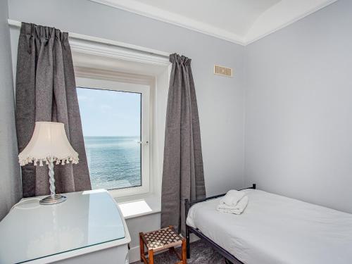 ドーリッシュにあるOcean View, Coastguard Cottagesの窓、ベッド、デスクが備わるベッドルーム1室が備わります。