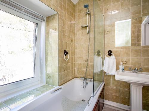 a bathroom with a shower and a tub and a sink at Ocean View, Coastguard Cottages in Dawlish