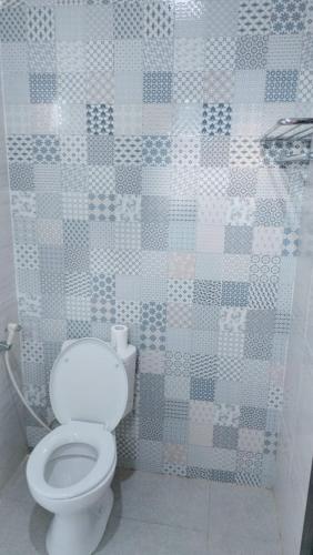 baño con aseo y pared de azulejos en Kenak guest house, en Ubud
