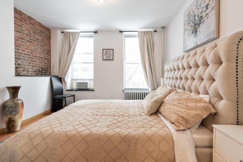 1 dormitorio con 1 cama grande y pared de ladrillo en 2BR/2Bath in Midtown East, en Nueva York