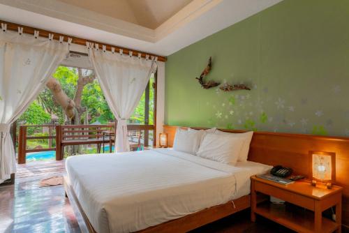 a bedroom with a large bed and a balcony at Baan Duangkaew Resort in Hua Hin
