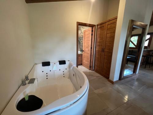 een groot wit bad in een kamer met een deur bij Cabaña Lunamiel 3 in Mazamitla