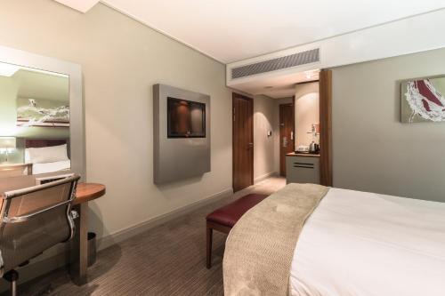 a hotel room with a bed and a desk at Holiday Inn Johannesburg-Rosebank by IHG in Johannesburg