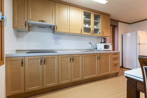 a kitchen with wooden cabinets and a white refrigerator at The Bay Jeju Resort in Seogwipo
