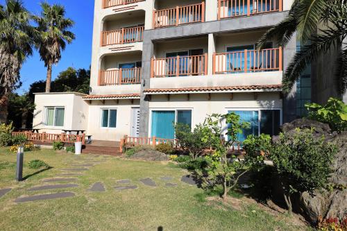 a large apartment building with balconies and a yard at The Bay Jeju Resort in Seogwipo