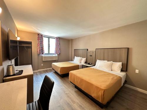 a hotel room with two beds and a desk at Regal Inn & Suites New York LaGuardia Hotel in Flushing