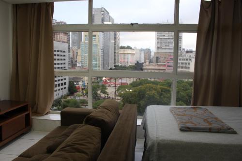 een slaapkamer met een bank en een groot raam bij Best View 1413 in Sao Paulo