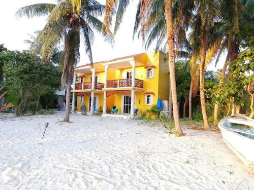 a yellow house on the beach with palm trees and a boat at Marysol private beach next to nomads d5 in Isla Mujeres