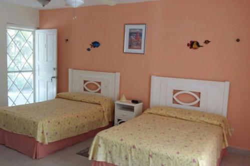 two beds in a bedroom with orange walls at Marysol private beach next to nomads d5 in Isla Mujeres